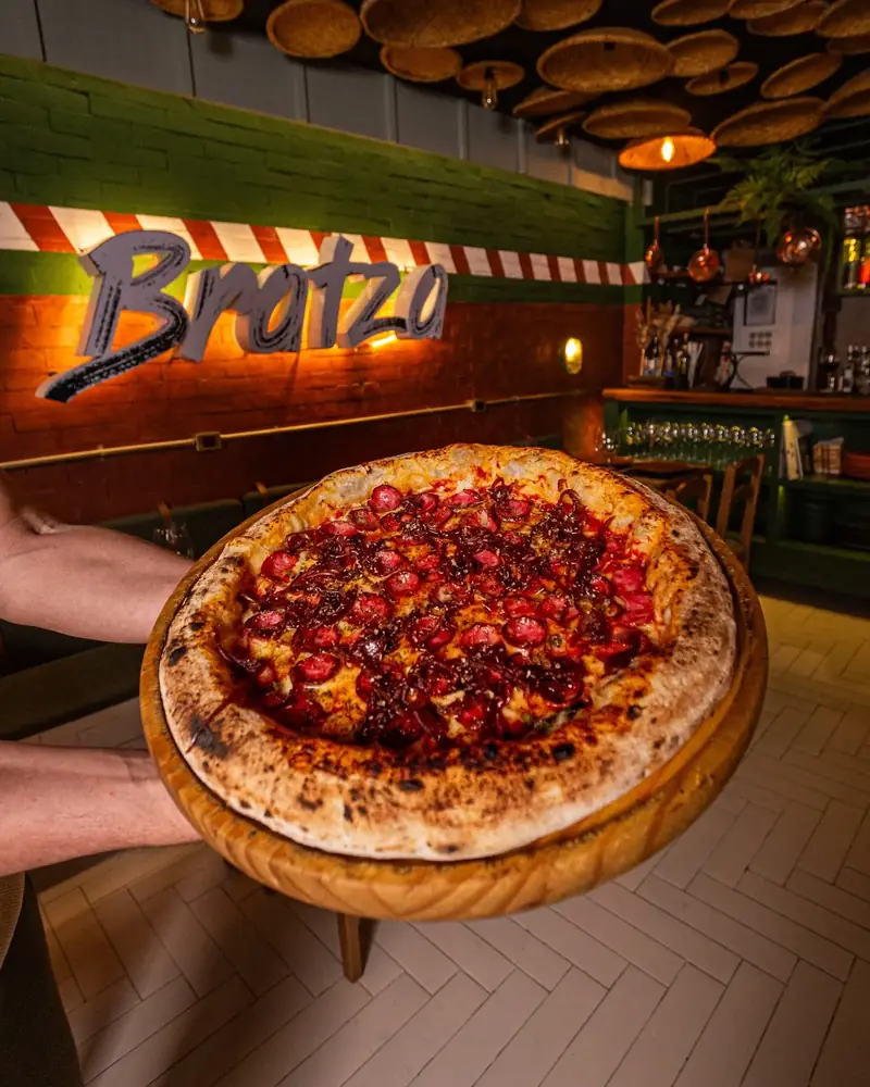 Calabratza no salão da Bratza, com o letreiro ao fundo